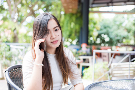 年轻迷人的亚洲女性谈论智能手机户外咖啡厅沟通理念
