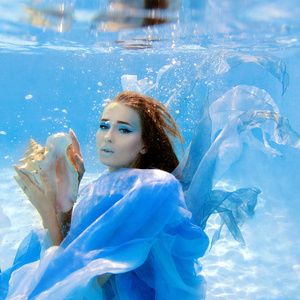 水下时尚的美丽的年轻女子，穿着蓝色衣服的肖像