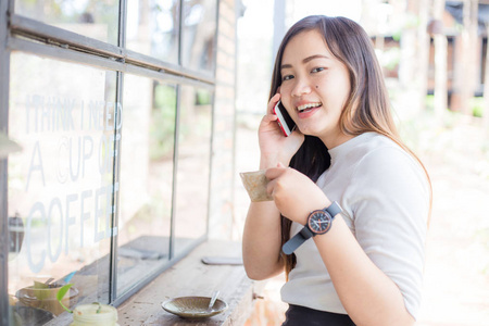 年轻迷人的亚洲女性谈论智能手机户外咖啡厅沟通理念