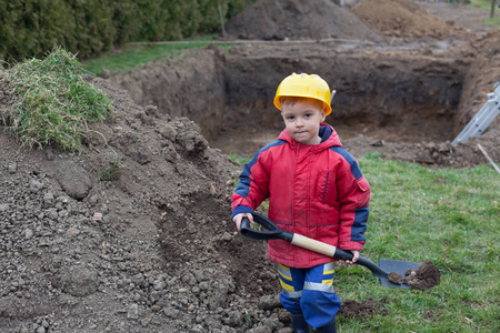 小男孩与一把铁锹帮助父母在池的构建