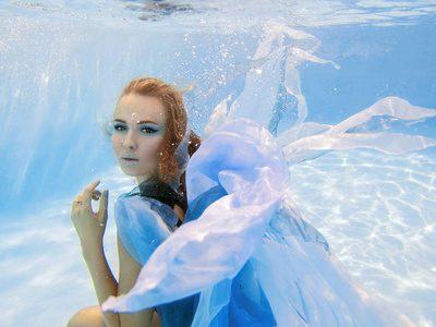水下时尚的美丽的年轻女子，穿着蓝色衣服的肖像