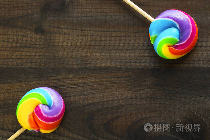 两个彩虹色棒棒糖在蓝色木背景