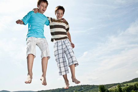 两个男孩在蹦床上跳跃