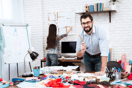 男性设计师有素描的想法, 而女人在裁缝店的订单工作