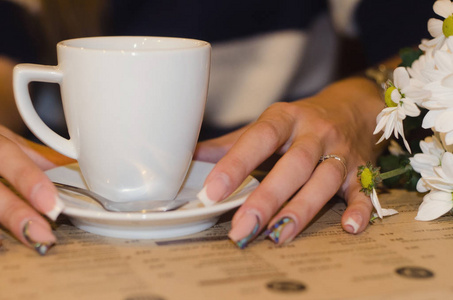 年轻女子捧在手里在咖啡馆的咖啡一杯