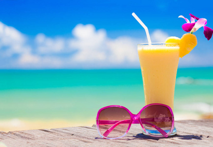 新鲜的香蕉和菠萝汁和太阳镜上热带海滩的图片