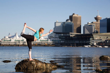 女子在赤柱公园练习瑜珈, 背景为市中心城市天际线。在加拿大不列颠哥伦比亚省温哥华拍摄