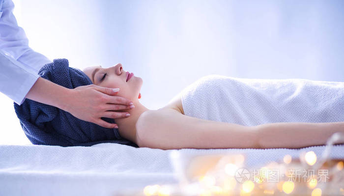 年轻女子躺在按摩床上,闭着眼睛放松.女人.spa 沙龙