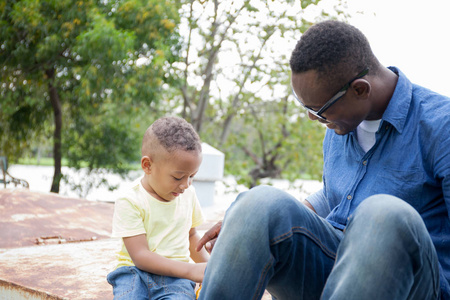 快乐的非洲裔美国父亲和儿子在室外公园一起享受快乐的时刻