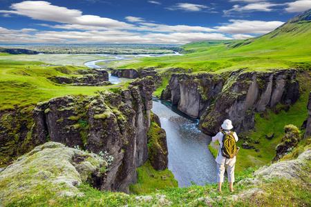在冰岛, 惊人的峡谷 Fyadrarglyufur。绿色的苔原在夏天。站在岩石上的老年妇女, 拍摄风景风景。北方旅游活动的概念