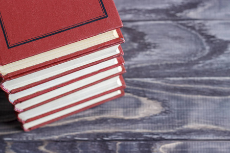 一堆红色的书放在一张木桌上。阅读习惯的概念