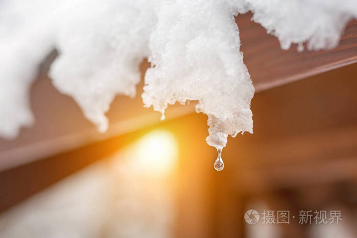 屋顶上融化的雪冰柱的特写.水滴下降.春天的开始.满足