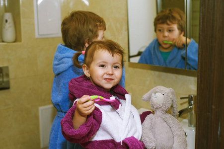 可爱的孩子在浴室的浴袍刷牙他们的牙齿