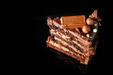 一块美味的巧克力蛋糕与奶油间层装饰巧克力糖果服务于黑色背景