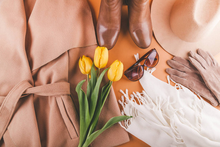 春天女性装备与黄色郁金香。橙色背景上的衣服鞋和配件套装
