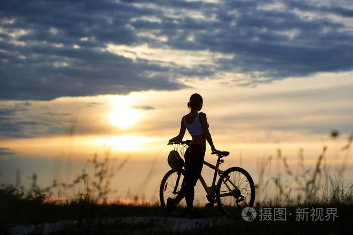 照片 运动骑自行车的剪影, 穿着运动服, 站在她的自行车上的踪迹.