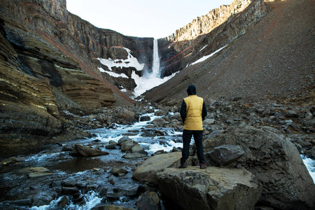 游客站在他的背上看着冰岛的瀑布。