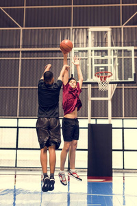 两个十几岁的男孩一起在球场上打篮球