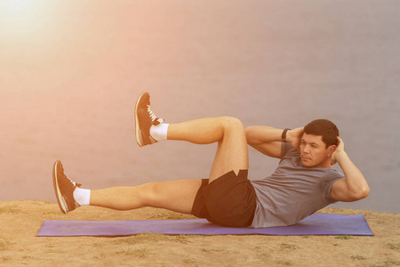 仰卧起坐健身人行使坐在夏天在草上外。适合工作交叉夏季训练的男运动员。在他 20 多岁的白种人的肌肉运动模型