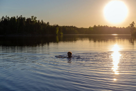 妇女在日落的森林湖游泳