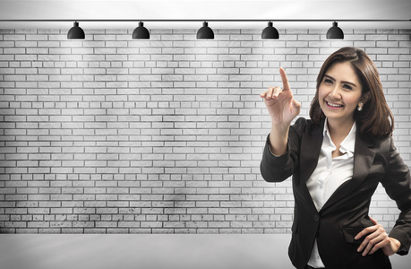 商业女人用她的手指触摸虚构。对砖与副本空间为您设计的背景墙上