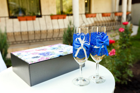 两个酒杯蓝丝带和礼品盒上婚礼典礼剪彩