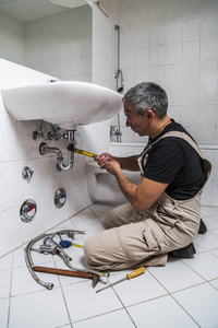 专业男性水管工修理卫生间的水龙头