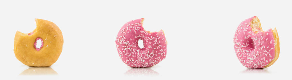 在白色的背景上, 一堆被咬的粉红色的粉色甜甜圈, 上面有白色的巧克力. 隔离在白色