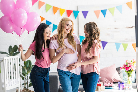 多文化女性接触怀孕的朋友腹部在婴儿聚会上