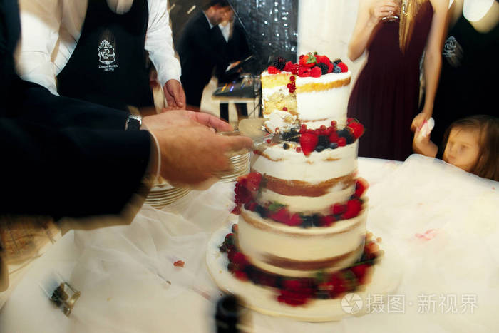 新婚夫妇切割完美的白色婚礼蛋糕 w 的 blurrd 图片