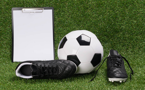 一个足球和一张纸的鞋子的结果是在一个绿色的草坪上
