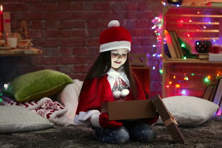 漂亮的小女孩坐在圣诞嘉年华服装装饰房间