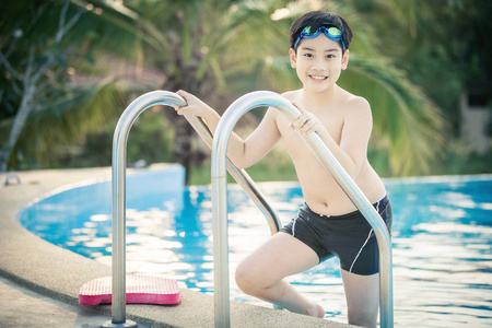 快乐的亚洲男孩在泳装上来池