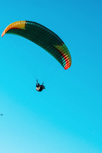 滑翔伞在明亮的阳光明媚的夏日里, 在蓝色晴朗的天空中飞上五颜六色的降落伞。积极的生活方式, 极端的运动。肾上腺素概念