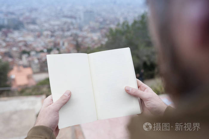 男子手拿着空旷的书, 视野模糊巴塞罗那城市背景