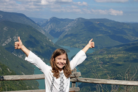 快乐的小女孩，与在山顶上竖起大拇指