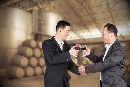 两个亚洲业务男子手持一杯酒和握手