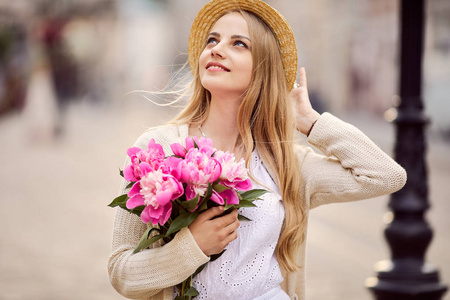 粉红色的花和帽子的年轻金发女郎
