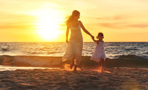 快乐家庭母亲和女儿运行 欢笑和在海滩玩耍