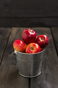 作物的金属桶上深色的木质背景中的红苹果