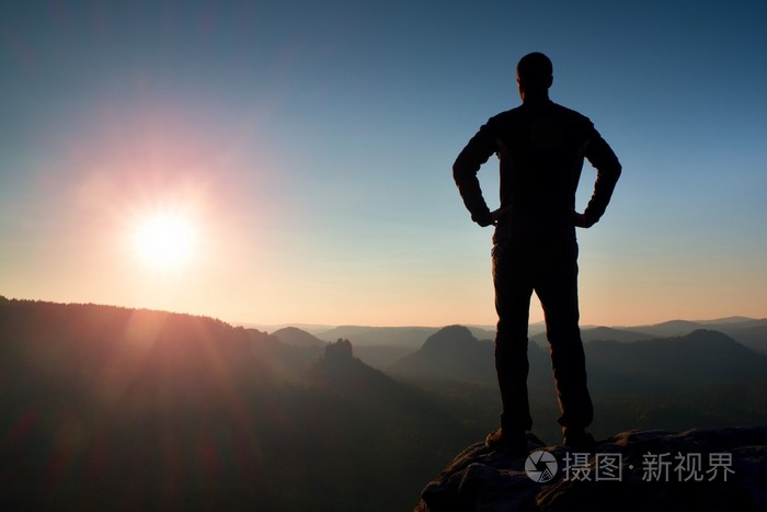 年轻的自信和强大男人,手放在臀部,早上或晚一天太阳与副本空间站的