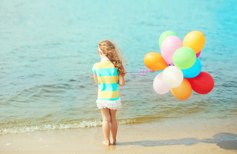 小女孩儿童用气球站在海边，视图的海滩上