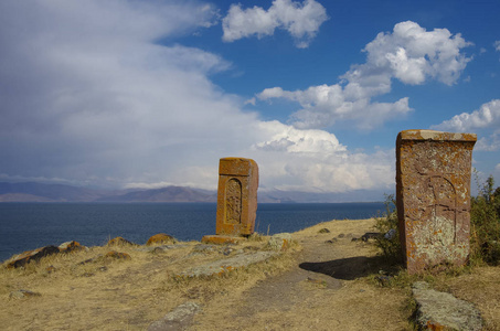 Khachkar 十字石 在塞凡湖，亚美尼亚。暴风雨的乌云和背景上的山峰