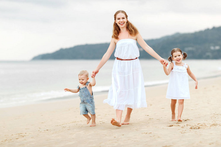 快乐家庭的母亲和孩子在夏天海边的沙滩上