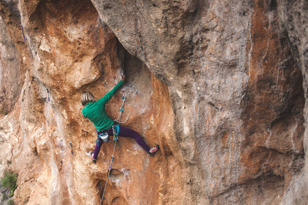 一个女人爬上岩石。攀登自然。户外健身。积极的生活方式。极限运动。运动员在自然的救援中训练