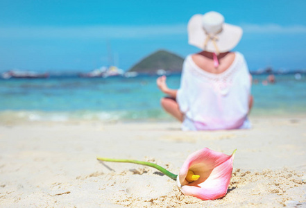 平静的女人在沙滩上沉思, 美丽的花朵