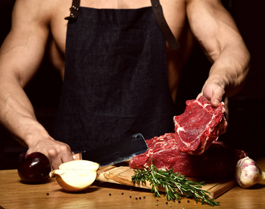 强壮的运动男子准备煮牛肉牛排肋骨在黑暗的厨房背景健康饮食概念黑色