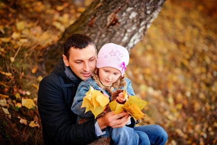 一位父亲抱着女儿婴儿在秋天的树林