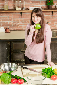 幸福的女人在厨房做饭。女人站在厨房的桌子旁边抱着一个绿色的苹果