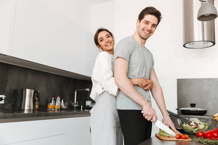 在厨房一起做饭的一对快乐的年轻夫妇的肖像
